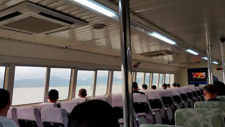 船舱内，马上到香港，人们都望向窗外，外面雾很大