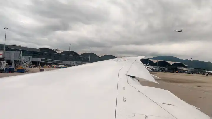 舷窗外的巨大机翼，斜上方有架客机刚刚启航